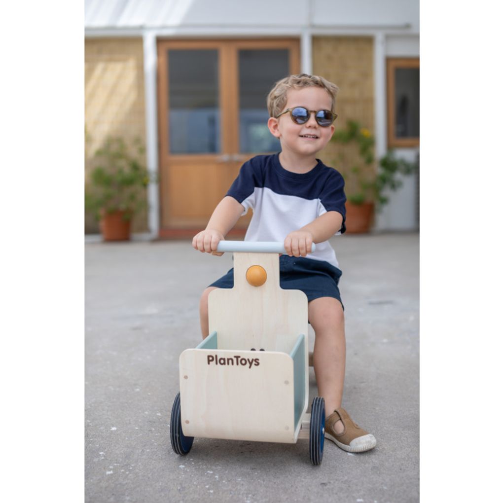 Kid playing PlanToys Delivery Bike - Orchard Collection เด็กกำลังเล่นรถส่งของขาไถแปลนทอยส์