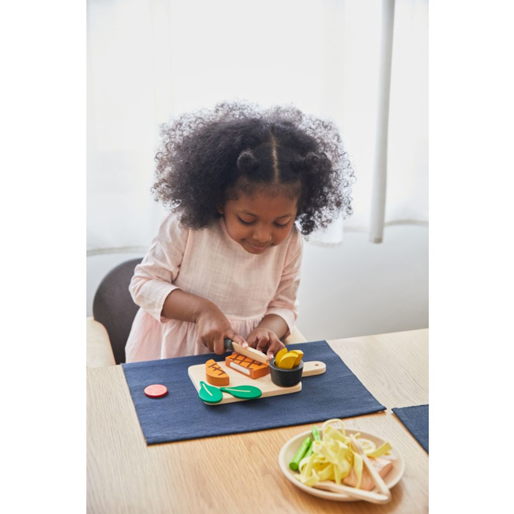 Kid playing PlanToys Steak Set เด็กกำลังเล่นชุดสเต็กแปลนทอยส์