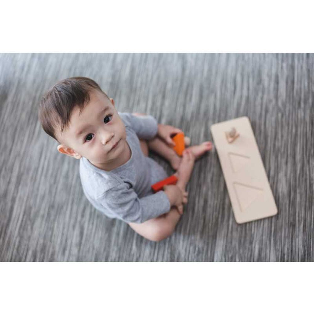 Kid playing PlanToys Triangle Matching Puzzle เด็กกำลังเล่นจิ๊กซอว์หมุดไม้รูปสามเหลี่ยมแปลนทอยส์