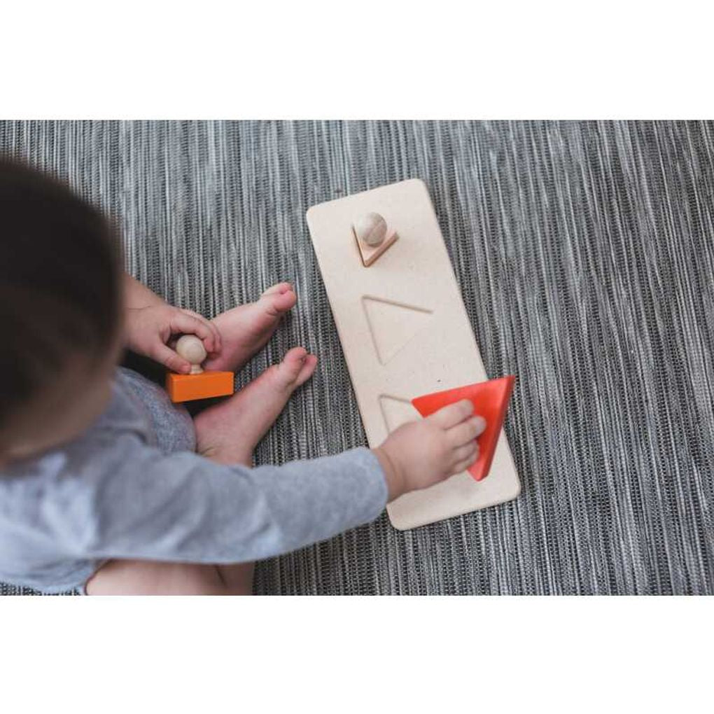 Kid playing PlanToys Triangle Matching Puzzle เด็กกำลังเล่นจิ๊กซอว์หมุดไม้รูปสามเหลี่ยมแปลนทอยส์