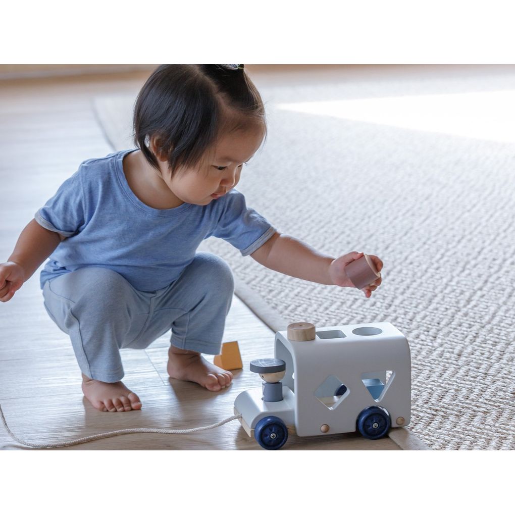 Kid playing PlanToys Sorting Bus - Orchard Series เด็กกำลังเล่นรถบัสหยอดรูปทรงแปลนทอยส์