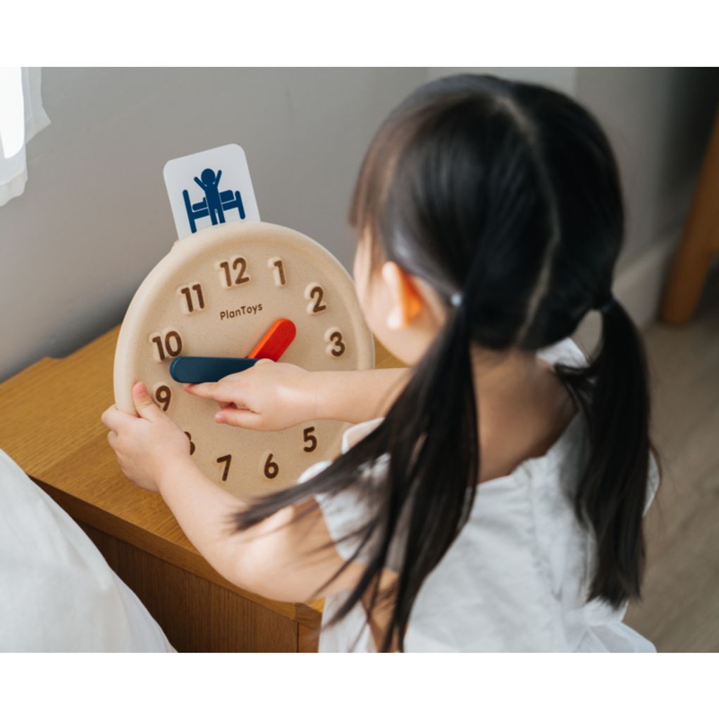 Kid playing PlanToys Activity Clock เด็กกำลังเล่นนาฬิกากิจวัตรประจำวันแปลนทอยส์