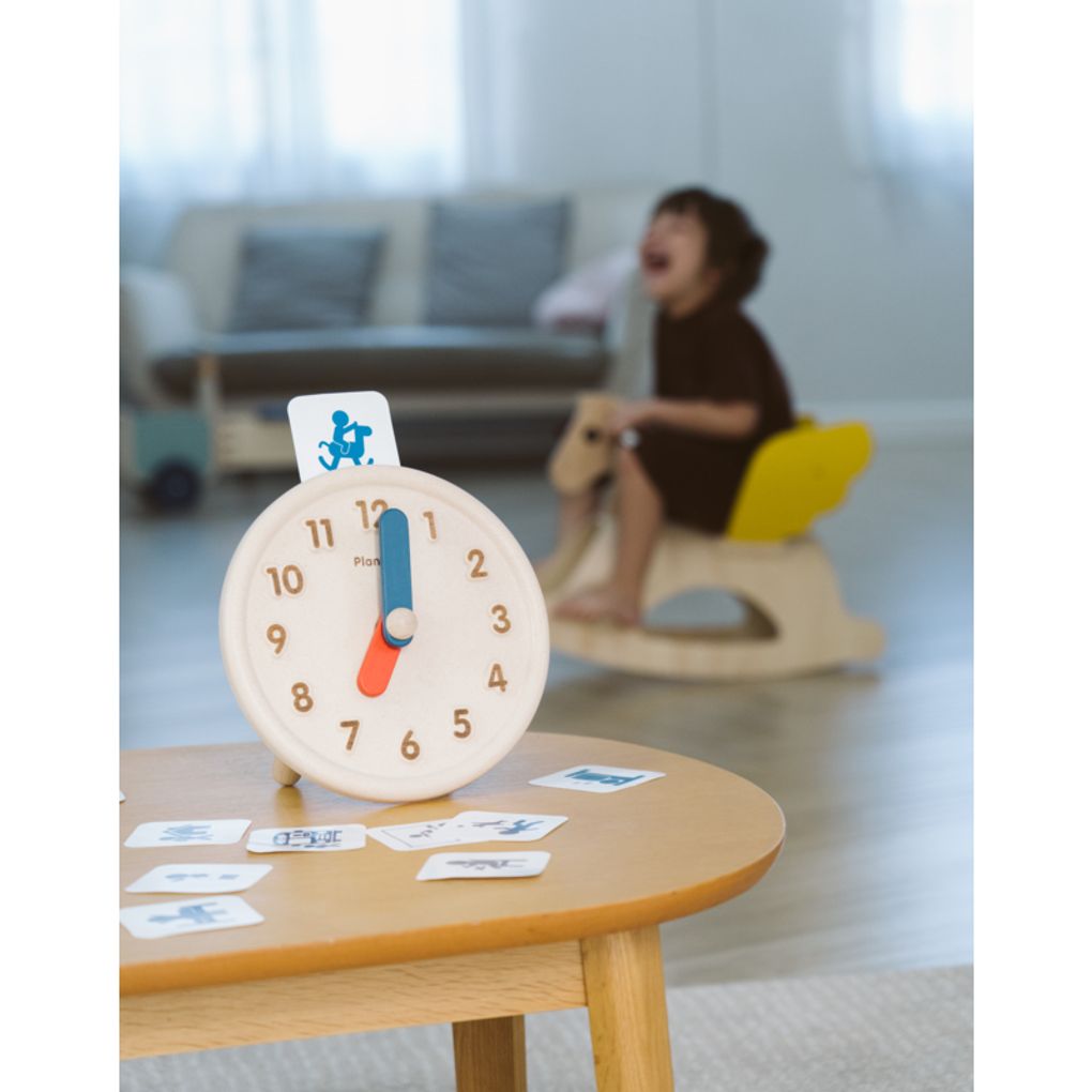 Kid playing PlanToys Activity Clock เด็กกำลังเล่นนาฬิกากิจวัตรประจำวันแปลนทอยส์