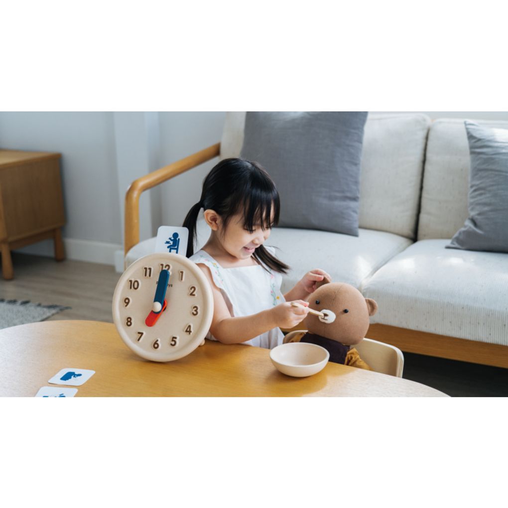 Kid playing PlanToys Activity Clock เด็กกำลังเล่นนาฬิกากิจวัตรประจำวันแปลนทอยส์